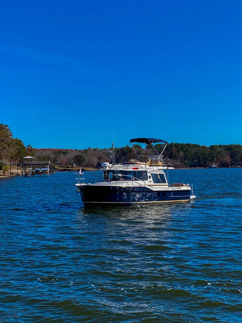 Slide: The Image of 2017 Ranger Tugs R-29 CB cruising on a serene lake under a clear blue sky. - 2