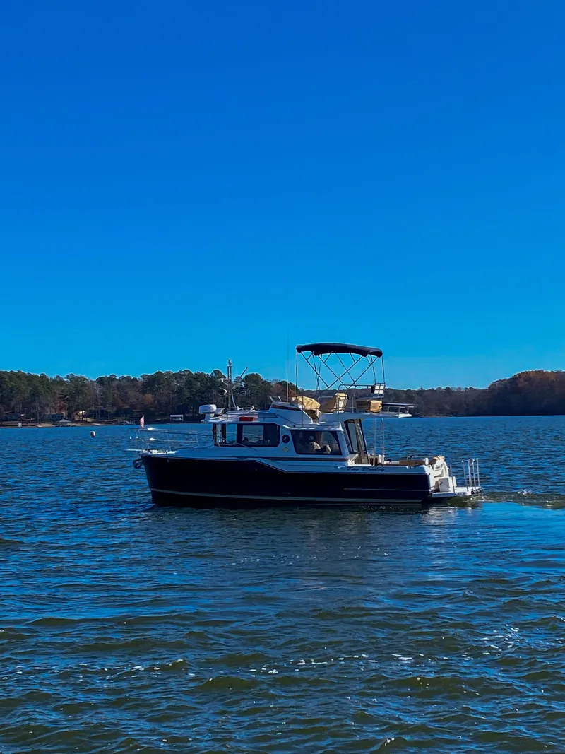 Slide: The Image of 2017 Ranger Tugs R-29 CB cruising on a serene lake under a clear blue sky. - 6