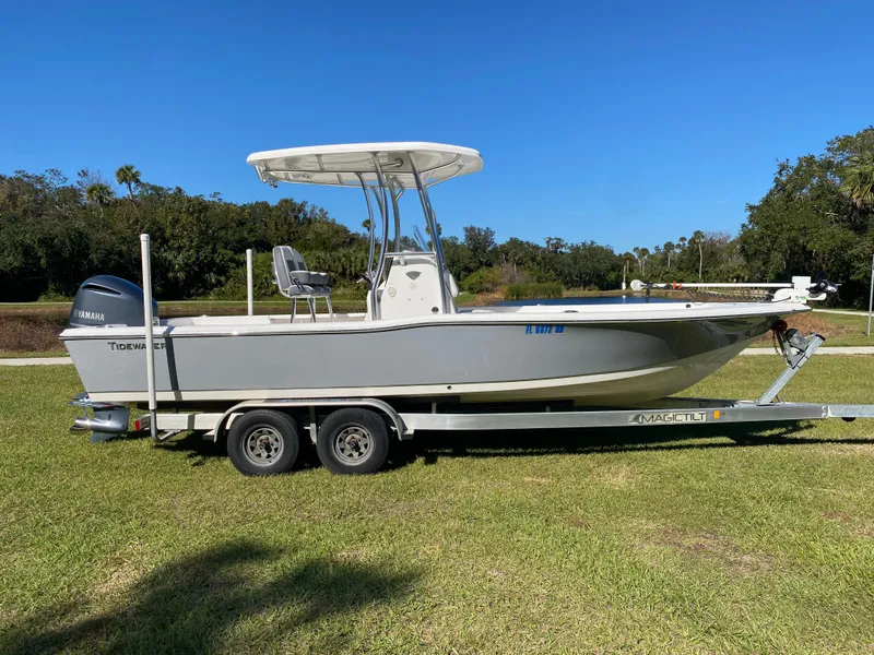Slide: The Image of 2018 Tidewater 2400 Bay Max boat on trailer, parked on grass under clear blue sky. - 2