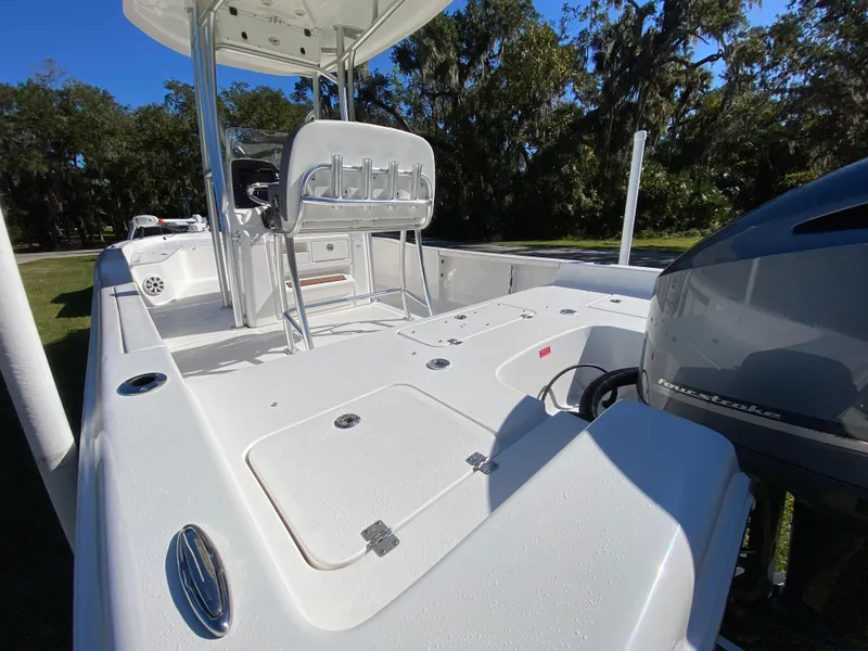 Slide: The Image of 2018 Tidewater 2400 Bay Max boat with spacious deck and seating, set against a wooded backdrop. - 28