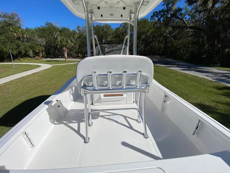 Slide: The Image of 2018 Tidewater 2400 Bay Max boat interior with rod holders, set against a scenic park backdrop. - 45