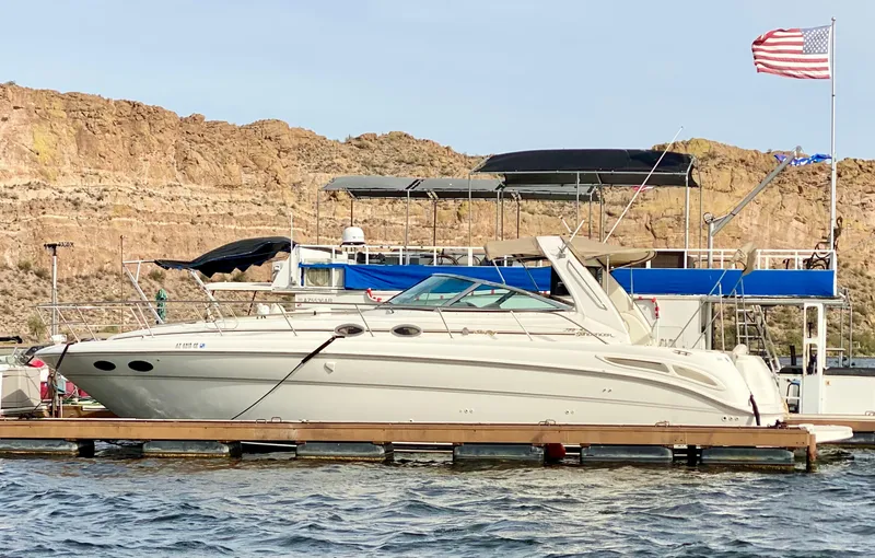 Slide: The Image of 2000 Sea Ray 380 Sundancer yacht docked by rocky shoreline with American flag. - 20