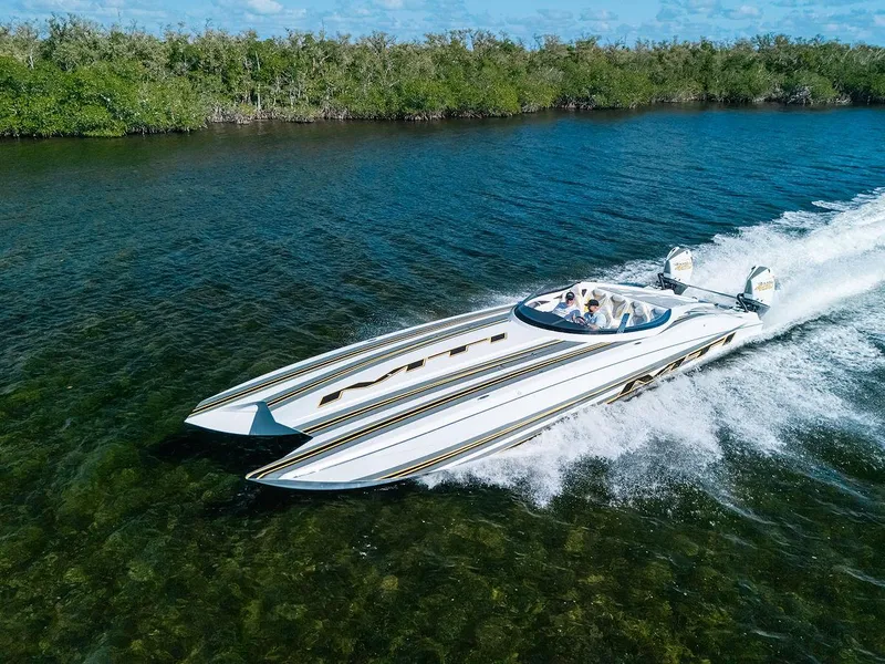 Slide: The Image of 2022 MTI 390X speedboat cruising on clear water near lush green shoreline. - 0