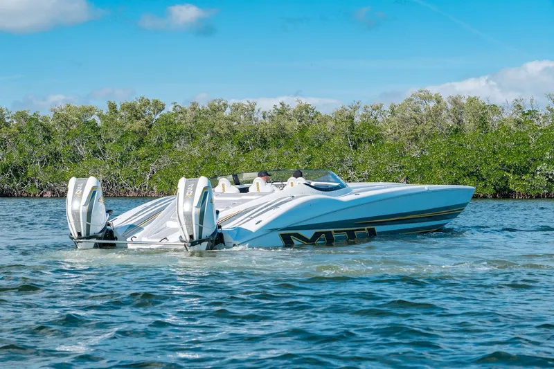 Slide: The Image of 2022 MTI 390X speedboat cruising on a sunny day near lush greenery. - 1
