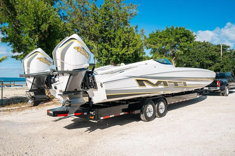 Slide: The Image of 2022 MTI 390X powerboat on trailer, dual engines, parked outdoors. - 4