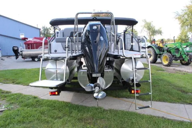 Slide: The Image of 2024 Harris Solstice 250 SL pontoon boat with powerful outboard motor, parked on grass. - 11