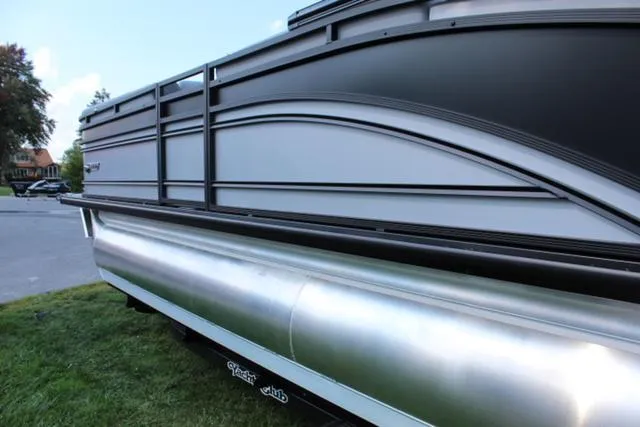 Slide: The Image of 2024 Harris Solstice 250 SL pontoon boat, sleek design, parked on grass. - 13