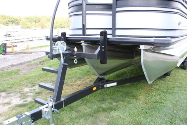 Slide: The Image of 2024 Harris Solstice 250 SL pontoon boat on trailer, parked on grass. - 14