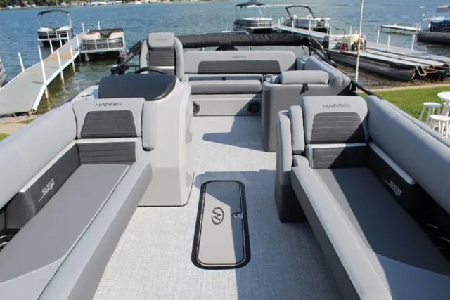 Slide: The Image of 2024 Harris Solstice 250 SL pontoon boat with spacious seating and modern design on a lake. - 15
