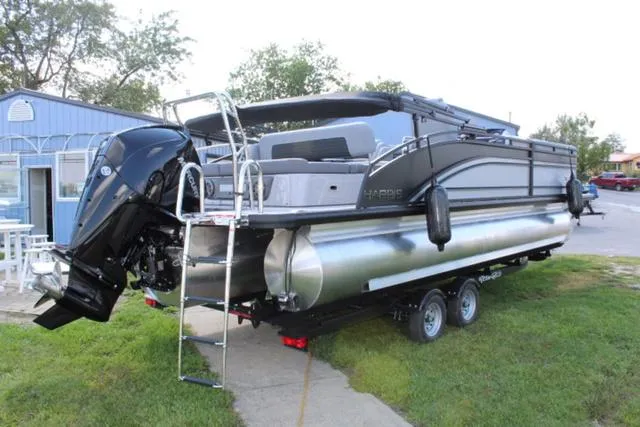 Slide: The Image of 2024 Harris Solstice 250 SL pontoon boat on trailer, parked on grass. - 5