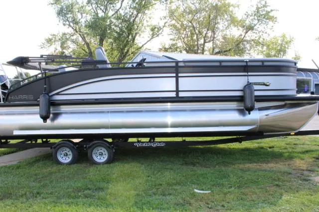 Slide: The Image of 2024 Harris Solstice 250 SL pontoon boat on trailer, parked on grass. - 6