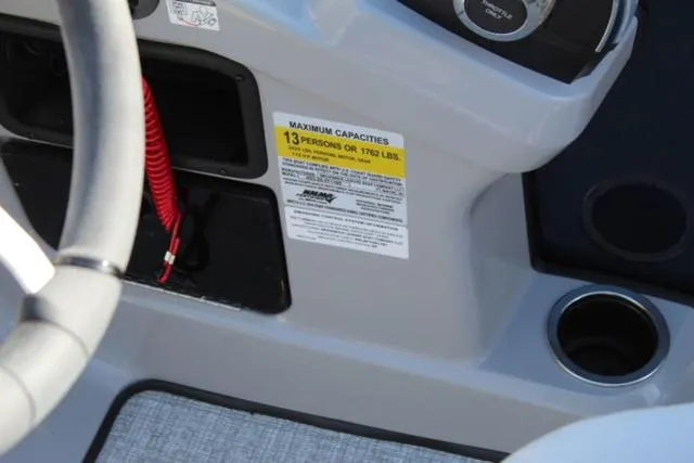 Slide: The Image of 2024 Harris Cruiser 230 CS boat dashboard with capacity label and cup holder. - 16