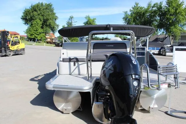 Slide: The Image of 2024 Harris Cruiser 230 CS pontoon boat with outboard motor, parked outdoors. - 6