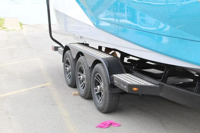 Slide: The Image of 2022 Nautique G23 Paragon boat trailer with triple axles on a paved surface. - 11