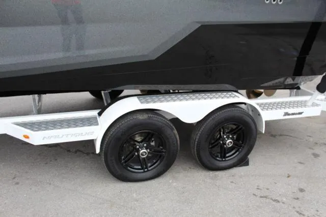 Slide: The Image of 2024 Nautique Super Air Nautique GS22 on a dual-axle trailer with black wheels. - 12