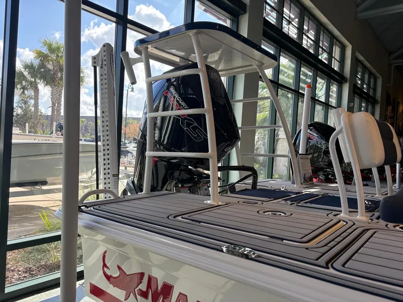 Slide: The Image of 2025 Mako 18 Pro Skiff Patriot Edition boat displayed indoors with motor and seating. - 2