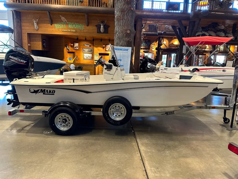 Slide: The Image of 2025 Mako Pro Skiff 15 CC boat displayed indoors on a trailer. - 1