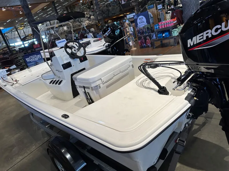 Slide: The Image of 2025 Mako Pro Skiff 15 CC boat with Mercury engine on display indoors. - 2