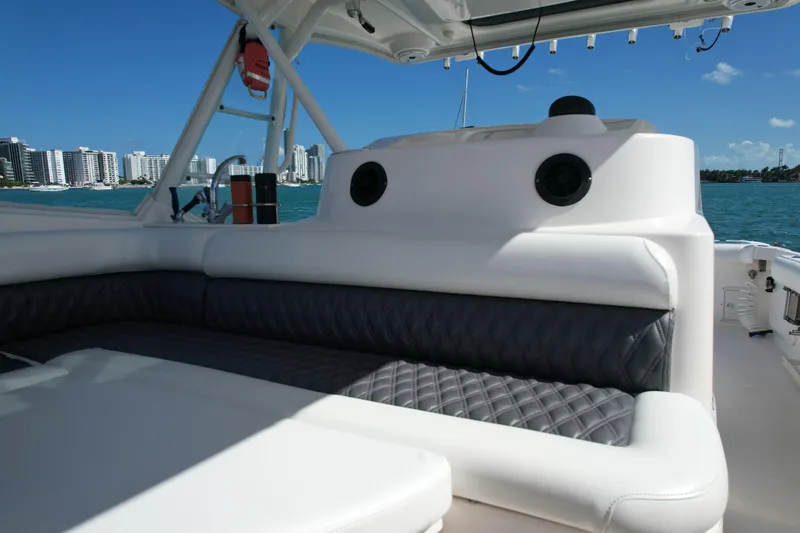 Slide: The Image of 2014 Everglades 350LX boat interior with cushioned seating, ocean view, and city skyline. - 49