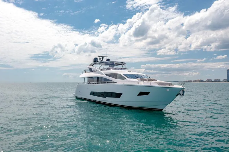 Slide: The Image of 2021 Sunseeker 86 Yacht cruising on open water under a partly cloudy sky. - 2