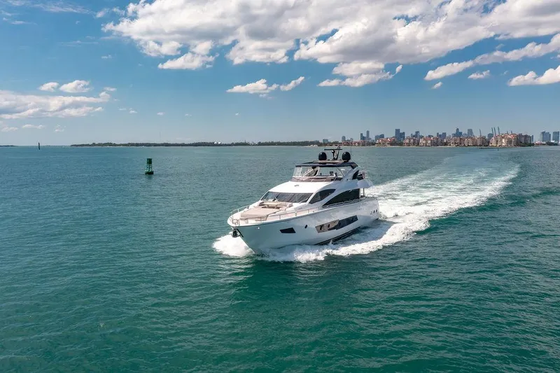 Slide: The Image of Sunseeker 86 Yacht 2021 cruising on open water with city skyline in background. - 8