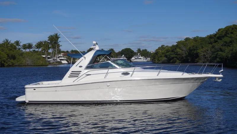 Slide: The Image of 2002 Sea Ray 340 Amberjack boat on a calm river with lush greenery. - 0