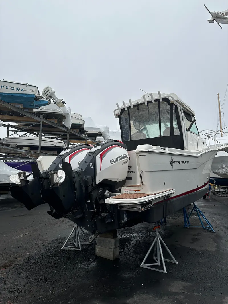 Slide: The Image of 2017 Striper 270 Walkaround boat with dual Evinrude engines on a dry dock. - 12