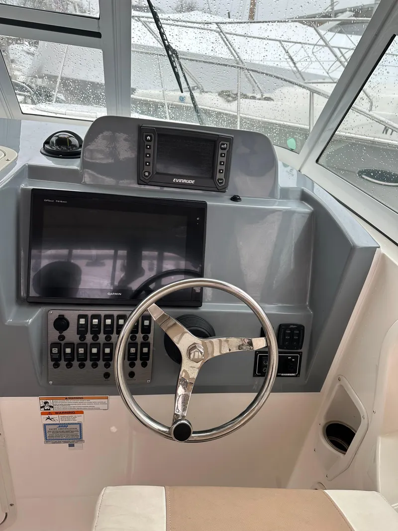 Slide: The Image of 2017 Striper 270 Walkaround boat dashboard with steering wheel and navigation screens. - 5