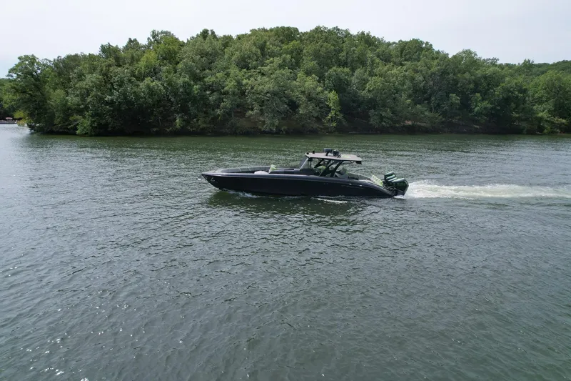 Slide: The Image of 2022 Midnight Express 43 Solstice boat cruising on a serene lake with lush green trees. - 3