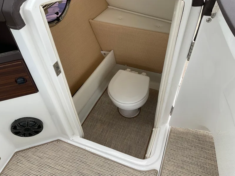 Slide: The Image of 2016 Cobalt R5 boat interior with compact marine toilet and beige carpeting. - 8