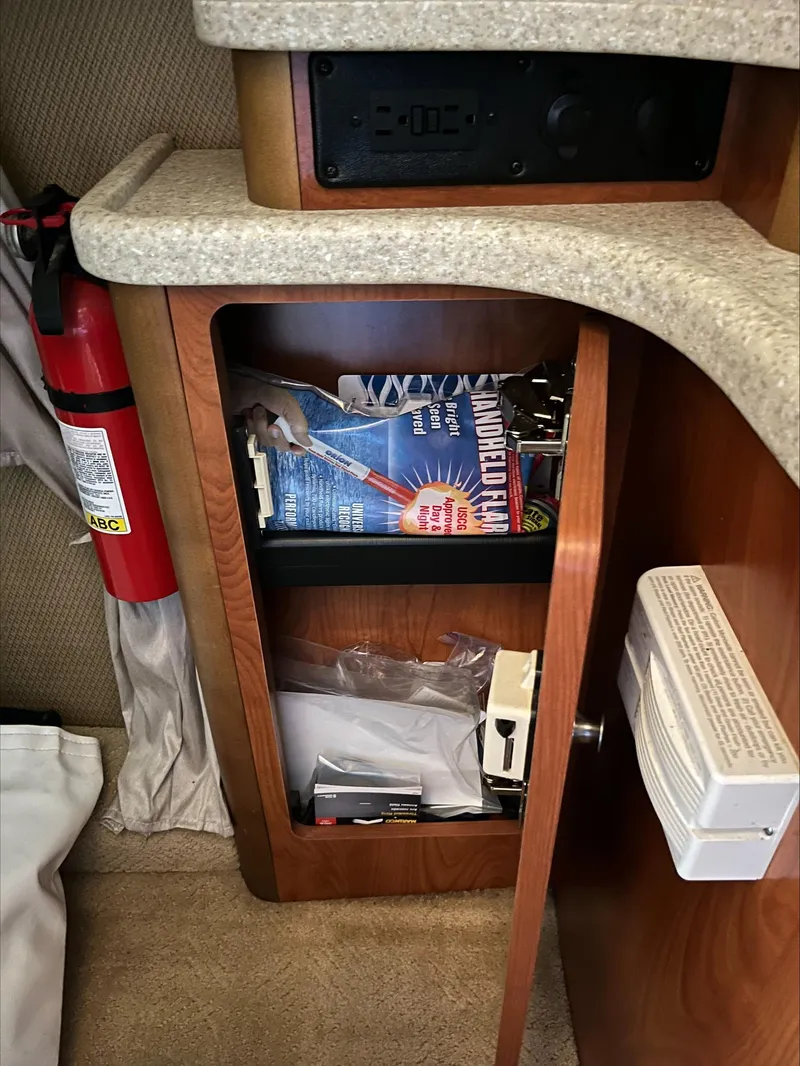Slide: The Image of 2008 Rinker 260 Express Cruiser interior cabinet with fire extinguisher and storage. - 11
