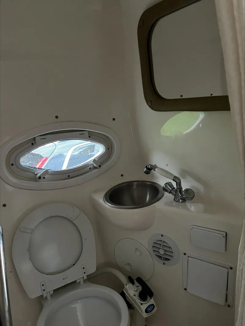 Slide: The Image of 2008 Rinker 260 Express Cruiser bathroom with toilet, sink, and porthole window. - 14