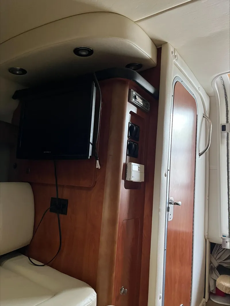 Slide: The Image of 2008 Rinker 260 Express Cruiser interior with TV and wooden cabinetry. - 15