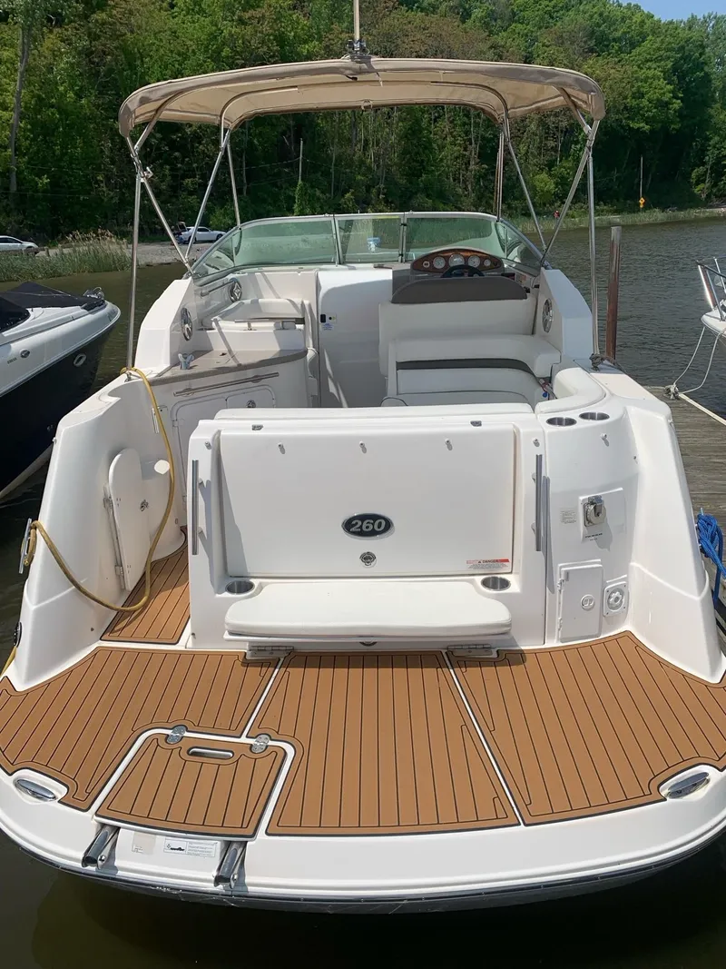 Slide: The Image of 2008 Rinker 260 Express Cruiser with tan deck, docked by a lush shoreline. - 4