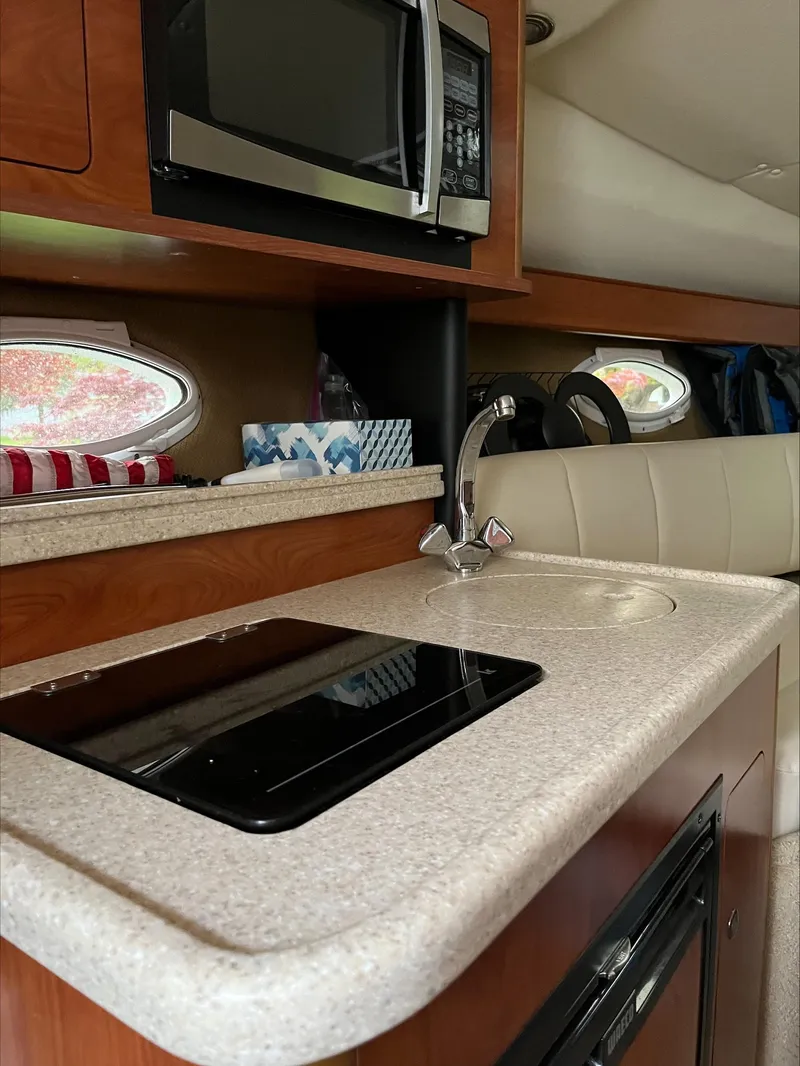 Slide: The Image of 2008 Rinker 260 Express Cruiser interior kitchen with microwave and sink. - 5