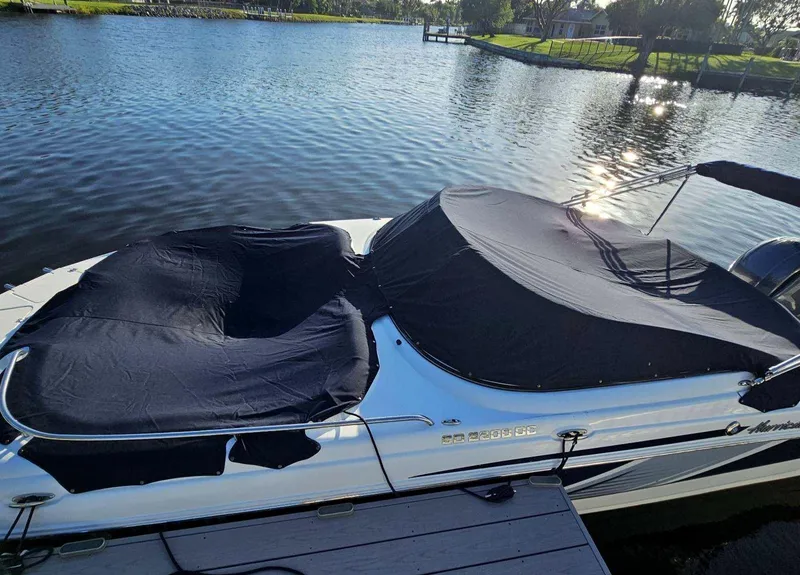 Slide: The Image of 2016 Hurricane SD2200 O/B boat with black covers docked on a serene lake. - 12