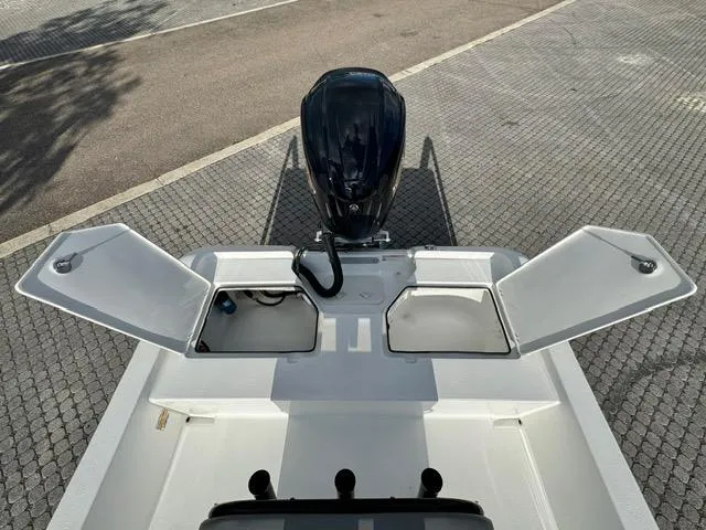 Slide: The Image of 2024 Action Craft 22 Coastal Bay boat with open storage compartments and outboard motor. - 23