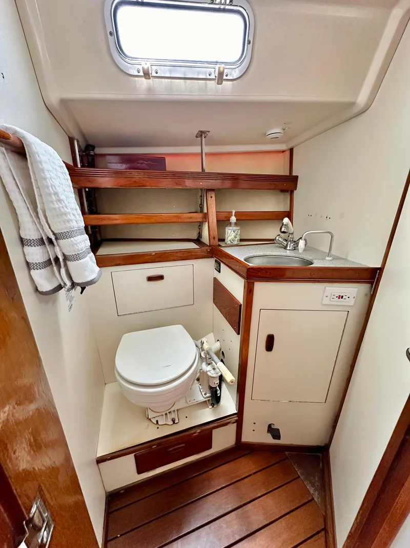 Slide: The Image of 1985 Sabre 36 yacht bathroom with wooden accents, sink, and toilet. - 13