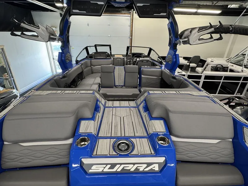 Slide: The Image of 2025 Supra SA 450 boat interior with gray seating and blue accents in a showroom. - 12