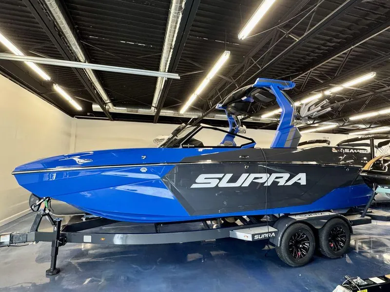 Slide: The Image of 2025 Supra SA 450 boat in showroom, blue and black design, on trailer. - 3