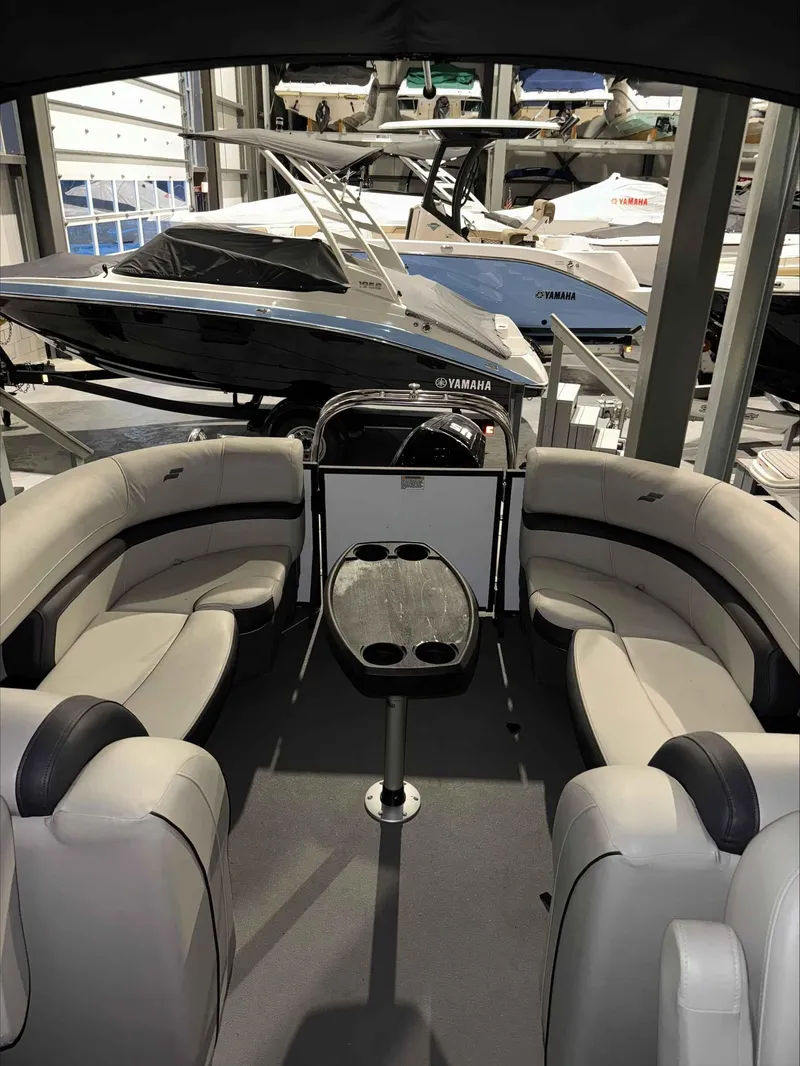Slide: The Image of 2022 Starcraft EXS 3 pontoon boat interior with seating and table, displayed in showroom. - 4
