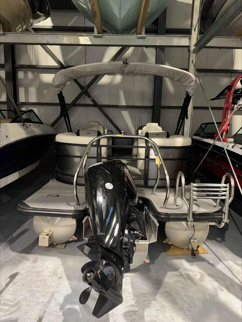 Slide: The Image of 2022 Starcraft EXS 3 pontoon boat in storage, featuring a powerful outboard motor. - 6