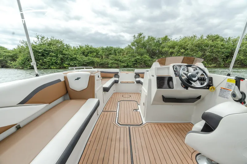 Slide: The Image of 2024 Starcraft SVX 211 OB boat interior with modern seating and steering, surrounded by lush greenery. - 8