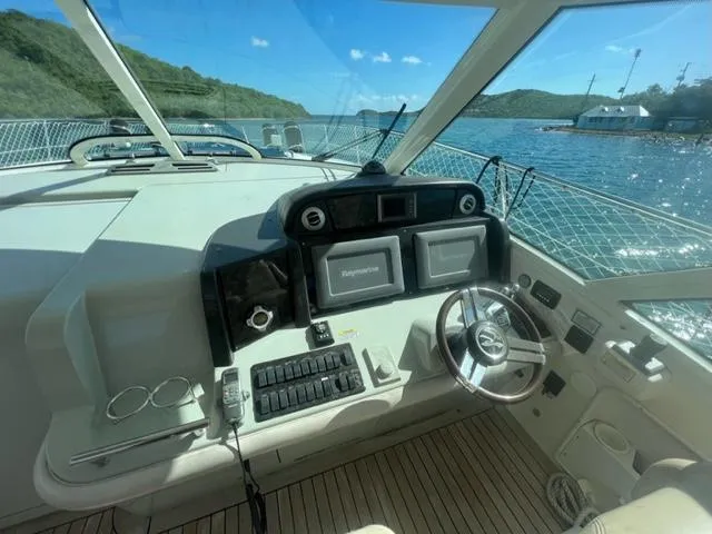 Slide: The Image of 2012 Sea Ray 500 Sundancer helm with navigation controls, overlooking scenic water and hills. - 2