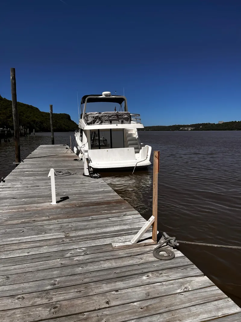 Slide: The Image of A 2001 Sandpiper 50 boat docked on a wooden pier under a clear blue sky. - 12