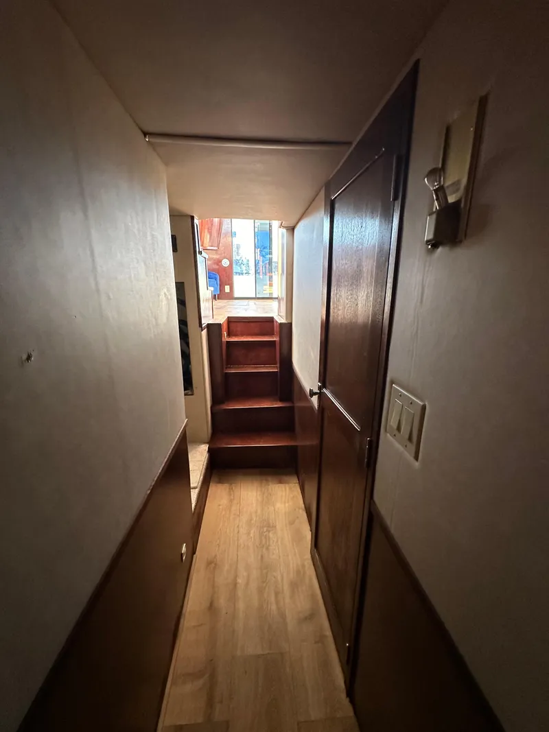 Slide: The Image of Narrow hallway in a 2001 Sandpiper 50, featuring wooden stairs and paneling. - 23