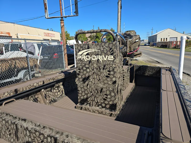 Slide: The Image of 2024 Pro-Drive X Series 1860 CC boat with camouflage design, parked outdoors. - 12