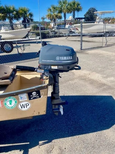 Slide: The Image of 1999 Gheenoe 13' boat with Yamaha outboard motor, parked near trailers and palm trees. - 7