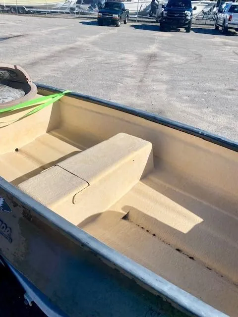 Slide: The Image of 1999 Gheenoe 13' boat interior with beige seating, parked outdoors. - 9