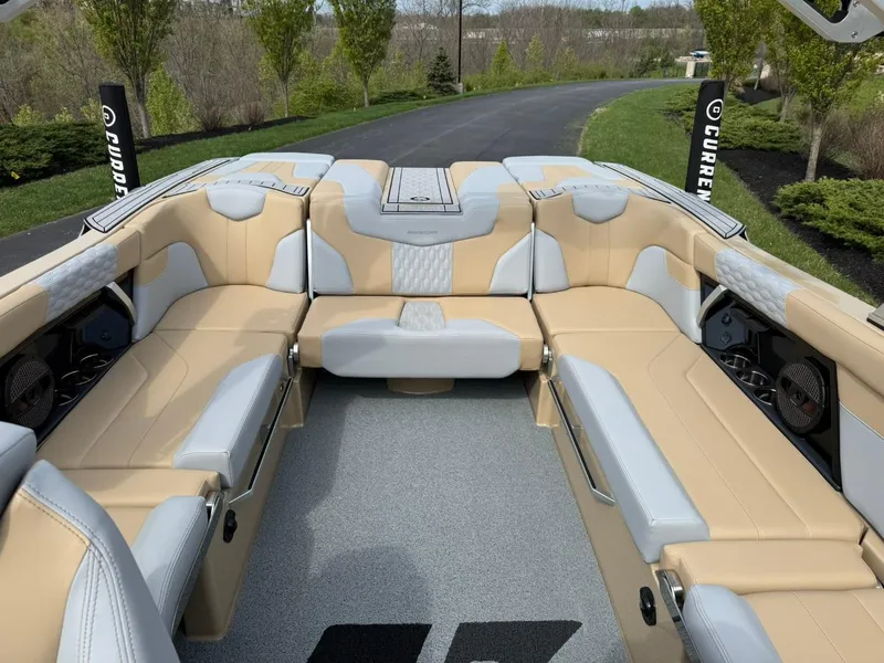 Slide: The Image of 2024 MasterCraft XT24 boat interior with beige and gray seating, surrounded by lush greenery. - 12